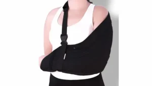 Pessoa utilizando tipoia para ombro preta para imobilização do braço durante tratamento de lesão ou recuperação ortopédica.