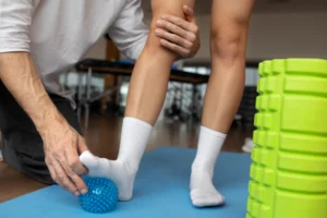 Fisioterapeuta auxiliando paciente em exercício de reabilitação com bola proprioceptiva para fortalecimento e recuperação dos membros inferiores