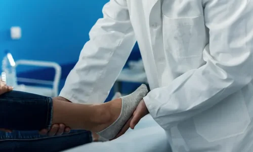 Ortopedista avaliando pé de paciente durante consulta para indicação de palmilha ortopédica e correção de alterações na pisada.