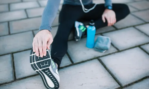 Atleta realizando alongamento antes do treino com produtos de suporte ortopédico para prevenção de lesões.