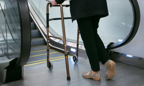 side-view-adult-with-walking-frame-near-escalators